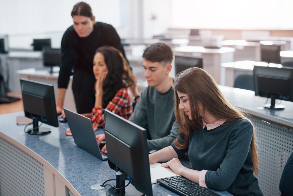 Jovens programadores em escritório moderno durante a formação em ADS, geração que estuda enquanto se discute se a inteligência artificial vai substituir programadores.