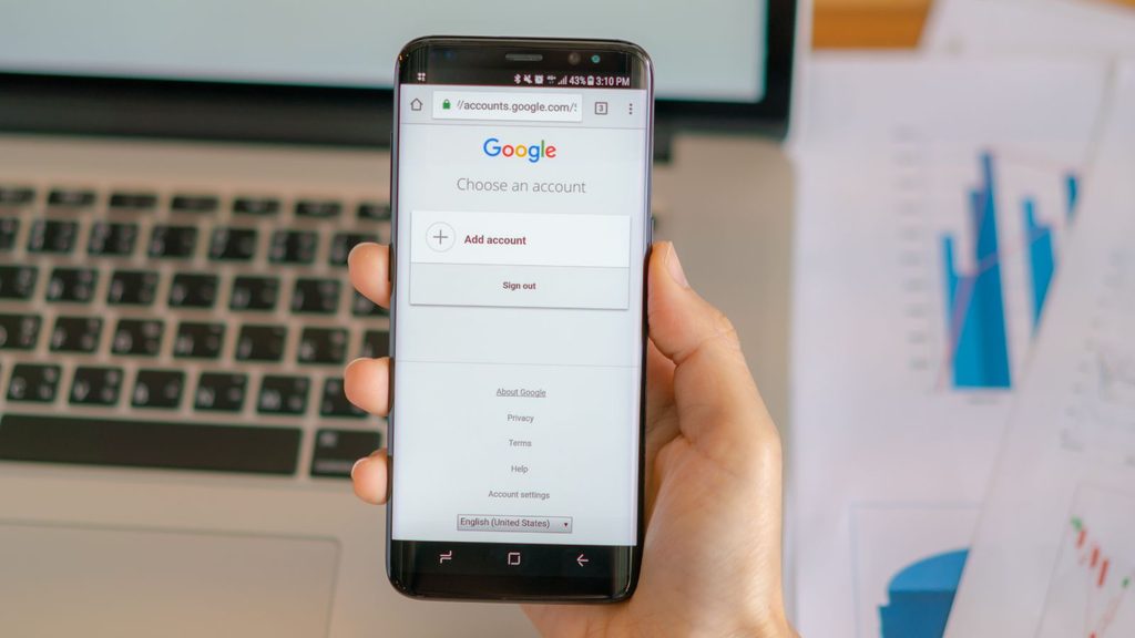 Mão segurando um smartphone com o aplicativo do Google aberto na tela, representando o momento em que o cliente pesquisa e compara antes de decidir.